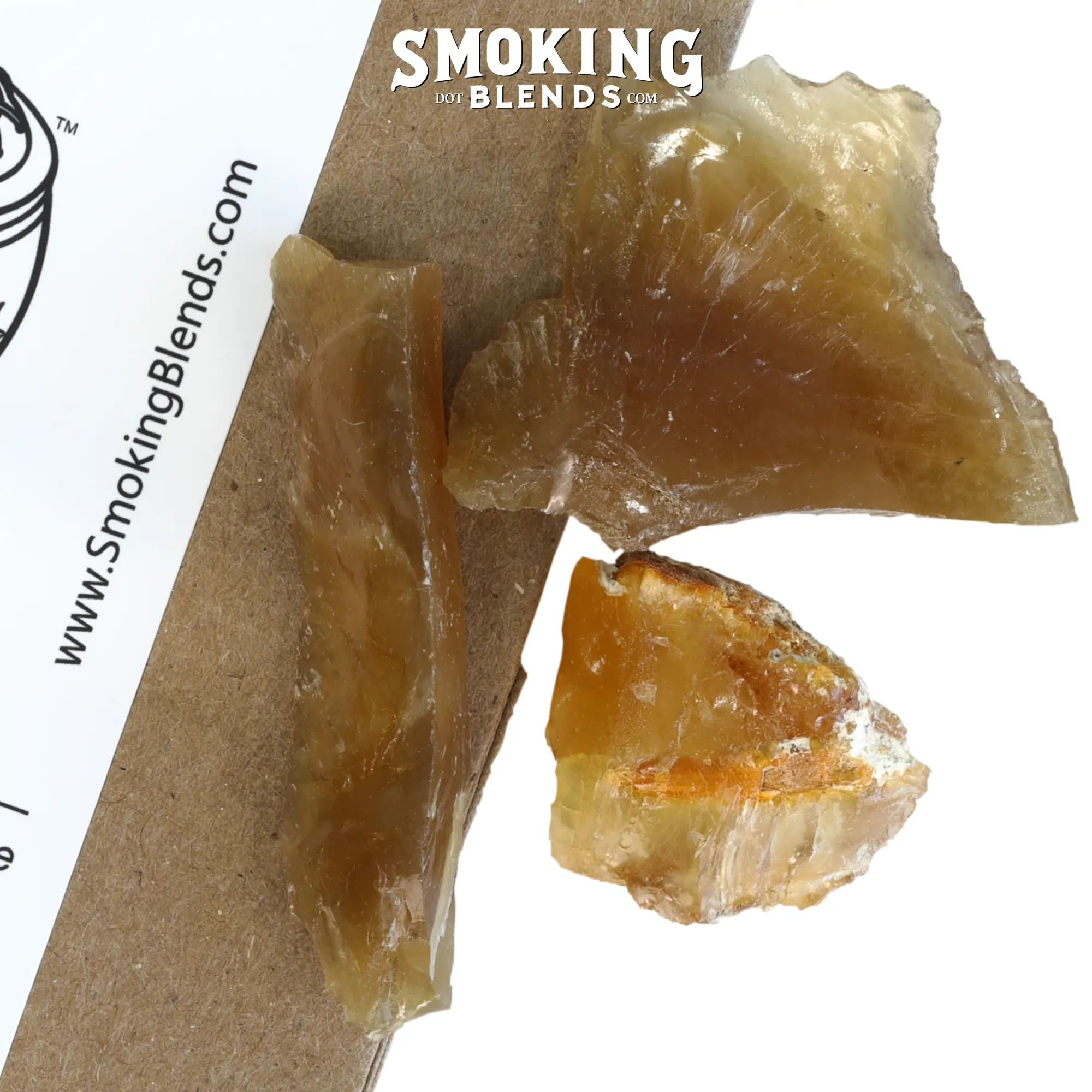 A close-up macro view of three pieces of amber resin showing their translucent golden color and hard, glass-like appearance.