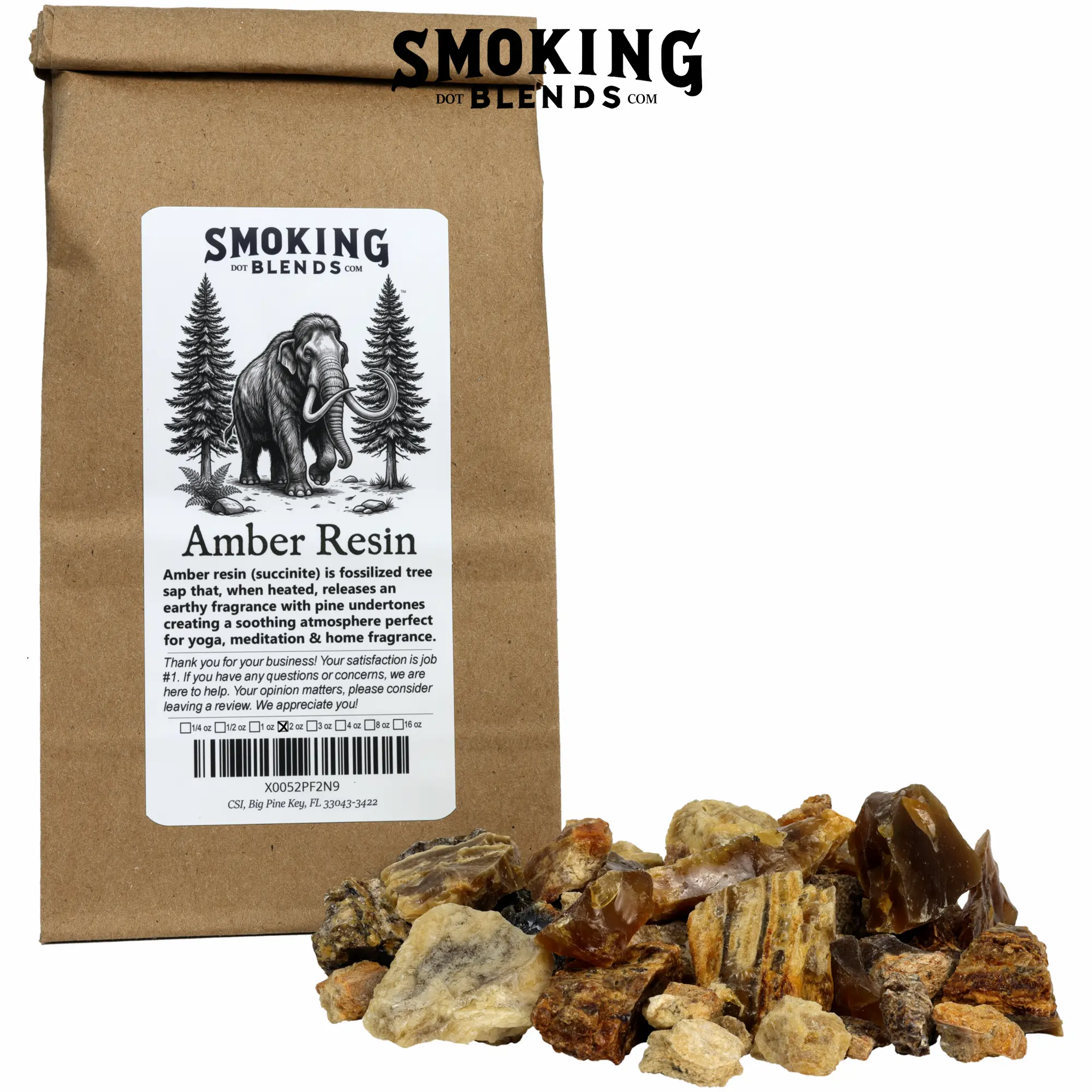 A tin-tie kraft paper bag with a white label featuring the SmokingBlends.com logo, an illustration of a mammoth walking through a pine forest, a product description, and a marked 2 oz box. A pile of amber resin incense chunks of mixed colors, including deep mahogany, golden amber, sandy tan, and pale yellow, sits in front of the bag. Pieces range from small pebbles to around an inch; some are smooth and glassy, others rough and matte.