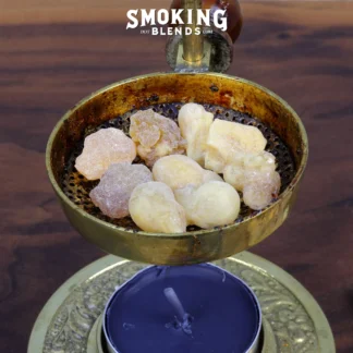 High-quality product image: close-up of a tealight candle incense burner filled with large chunks of frankincense. There is an unlit purple candle sitting in the burner.