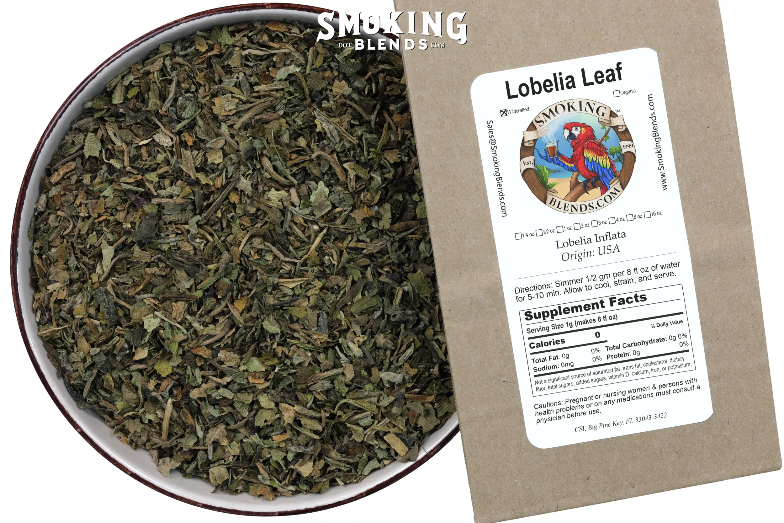 View looking down at a bowl of loose dried Lobelia leaf on the left, paired with the SmokingBlends.com product packaging angled sharply on the right, clearly displaying the "Lobelia Leaf" brand label and supplement information.