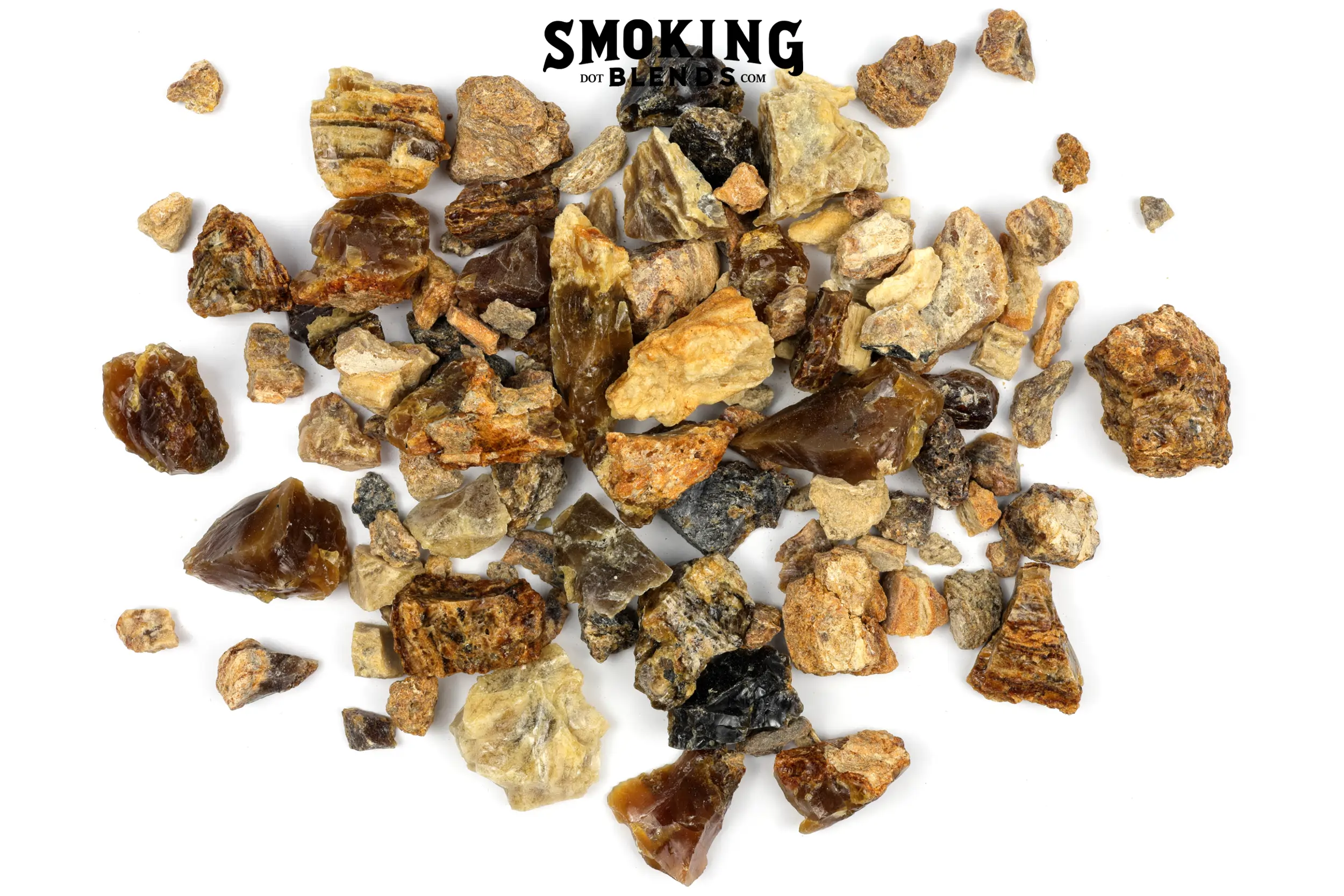 A pile of amber resin incense chunks of mixed colors, including deep mahogany, golden amber, sandy tan, and pale yellow. Pieces range from small pebbles to around an inch and a half; some are smooth and glassy, others rough and matte. At the top of the image, there is a black watermark that says Smoking Blends dot com.